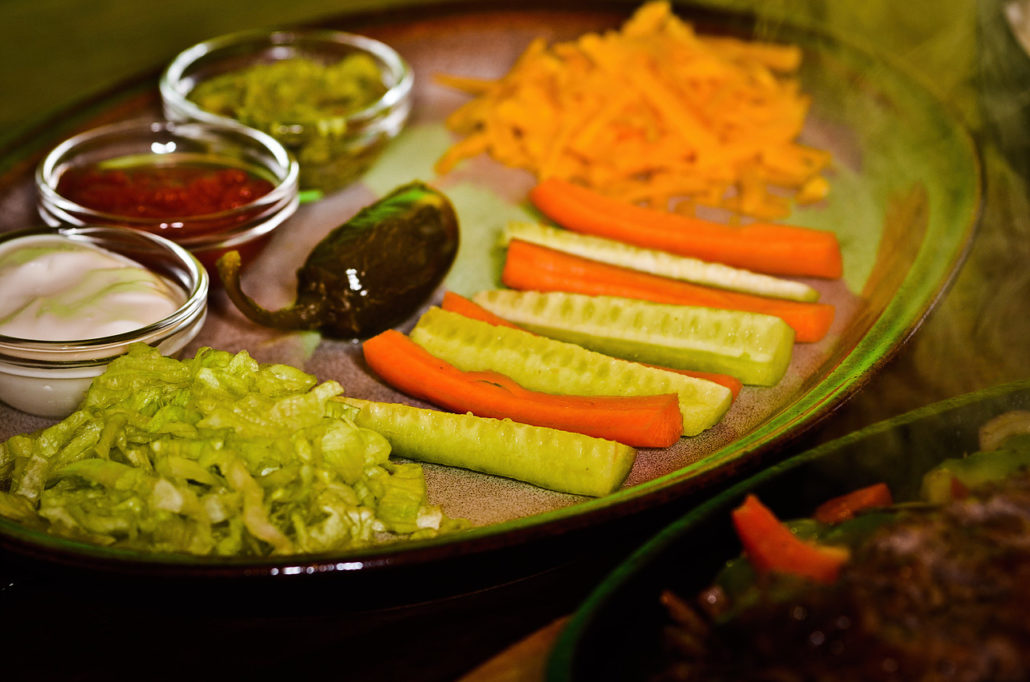 Misky se salsou, guacamole a strouhaným sýrem k fajitas