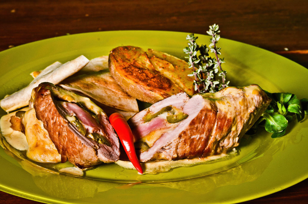 Plněné maso se šunkou, tortilla a chilli paprička na zeleném talíři