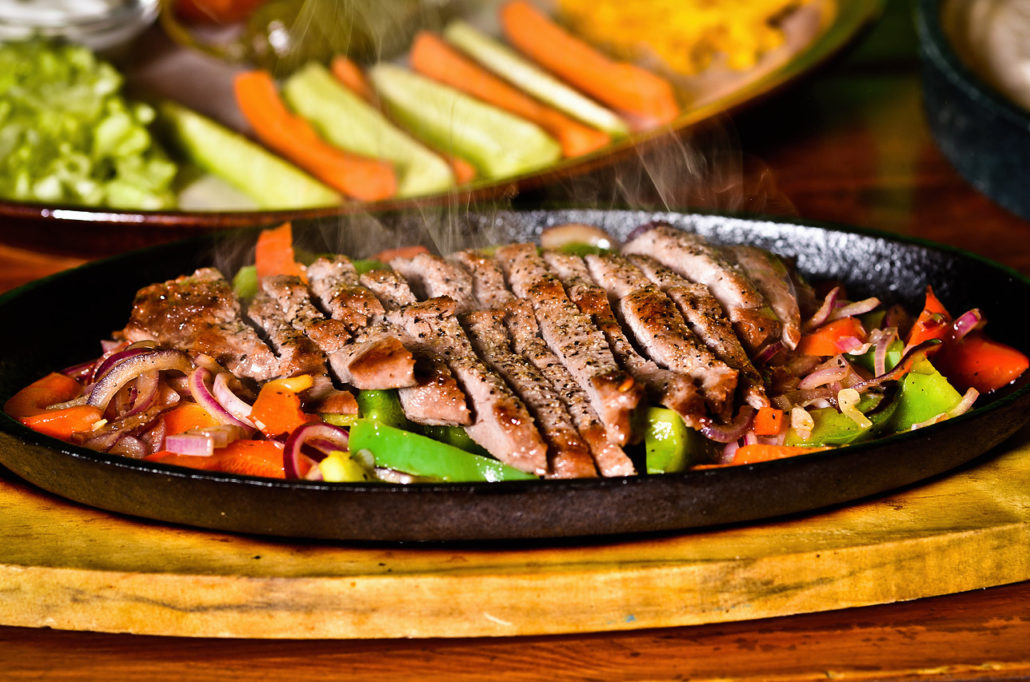 Fajitas s plátky masa a opečenou zeleninou na rozpálené pánvi